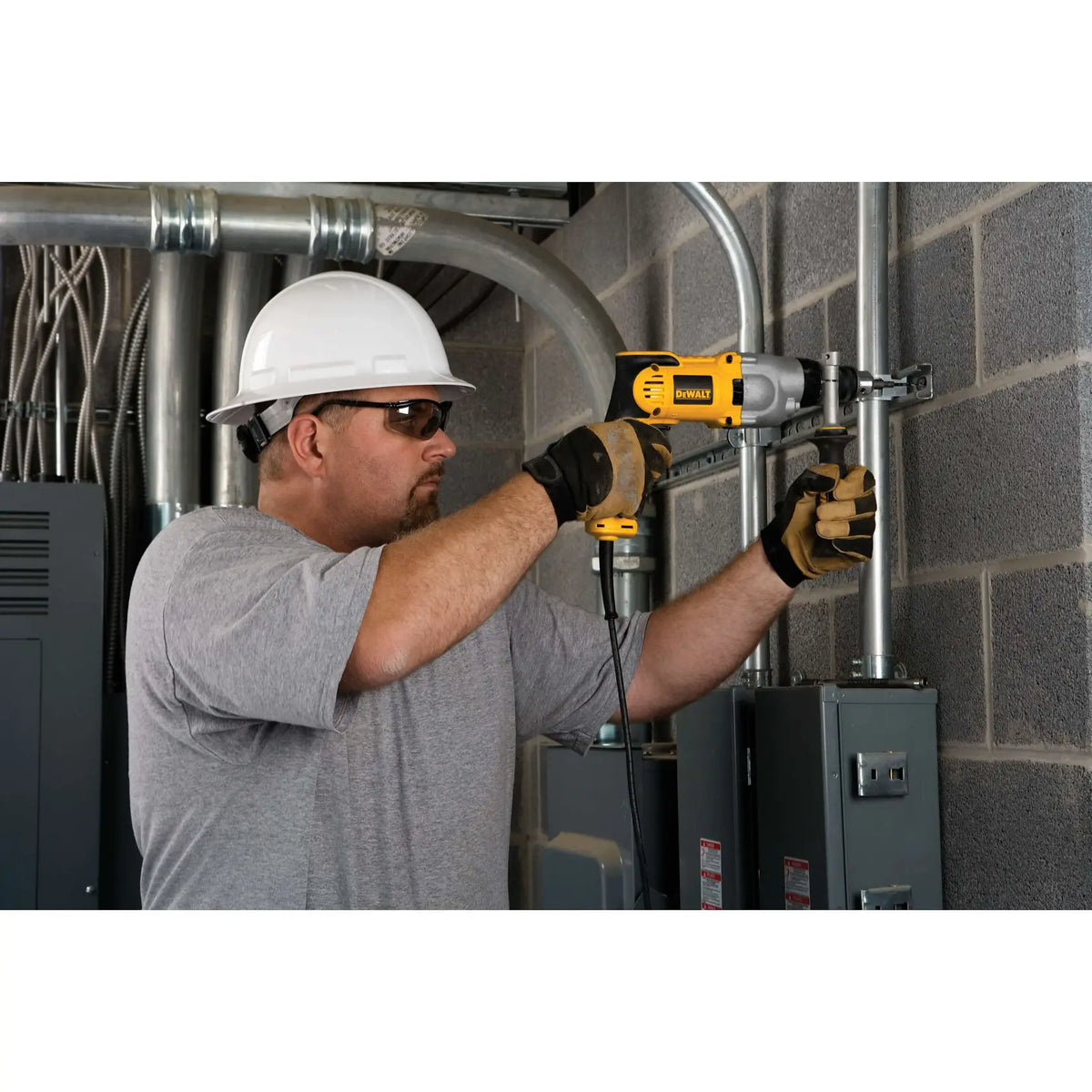 DEWALT DWD520 en uso sobre tuberías metálicas en pared de ladrillo